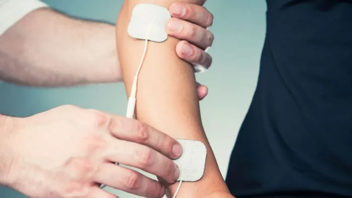 Chuyên viên đặt miếng điện cực để điều trị bằng các dòng điện xung trên cánh tay người bệnh
